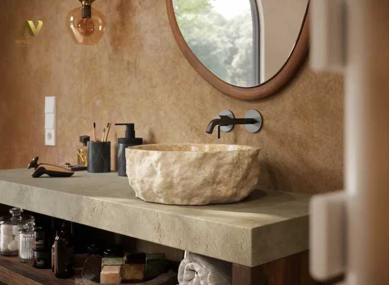 Rendu 3D photoréaliste en gros plan d’une vasque en pierre brute posée sur un plan minéral, avec robinetterie murale noire, miroir rond, suspension ambrée et accessoires de salle de bain sur fond d’enduit ocre texturé.